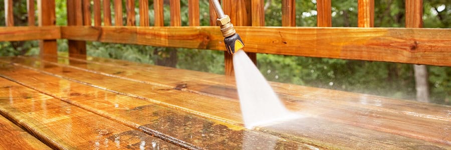 Pressure Washer Tune-Up Services Pressure washer cleans away dirt and grime on a backyard deck.