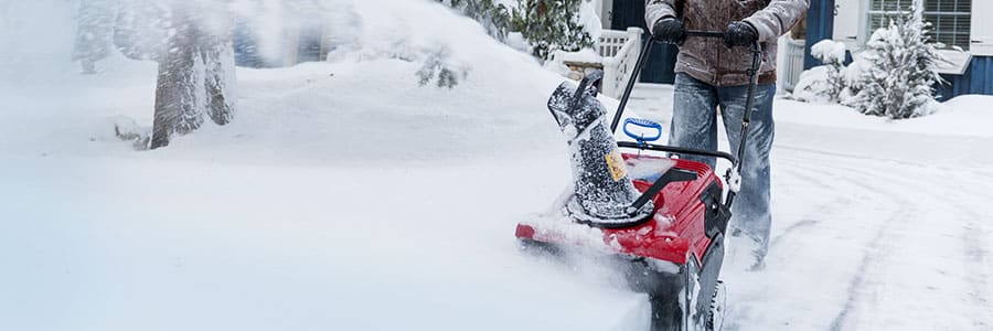 Homeowners uses snowblower to clear snow off his driveway.