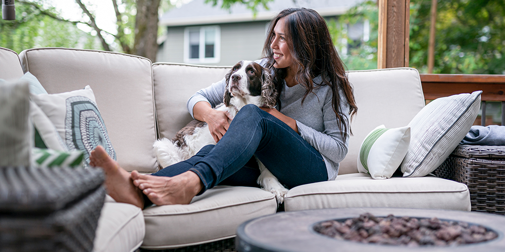 Outdoor Patio Ideas Beautiful female homeowner plays with dog on outdoor patio couch.